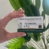 Hand holding a white EV charging card with 'EV CONEXION' and charging icon, plant leaves in the background.